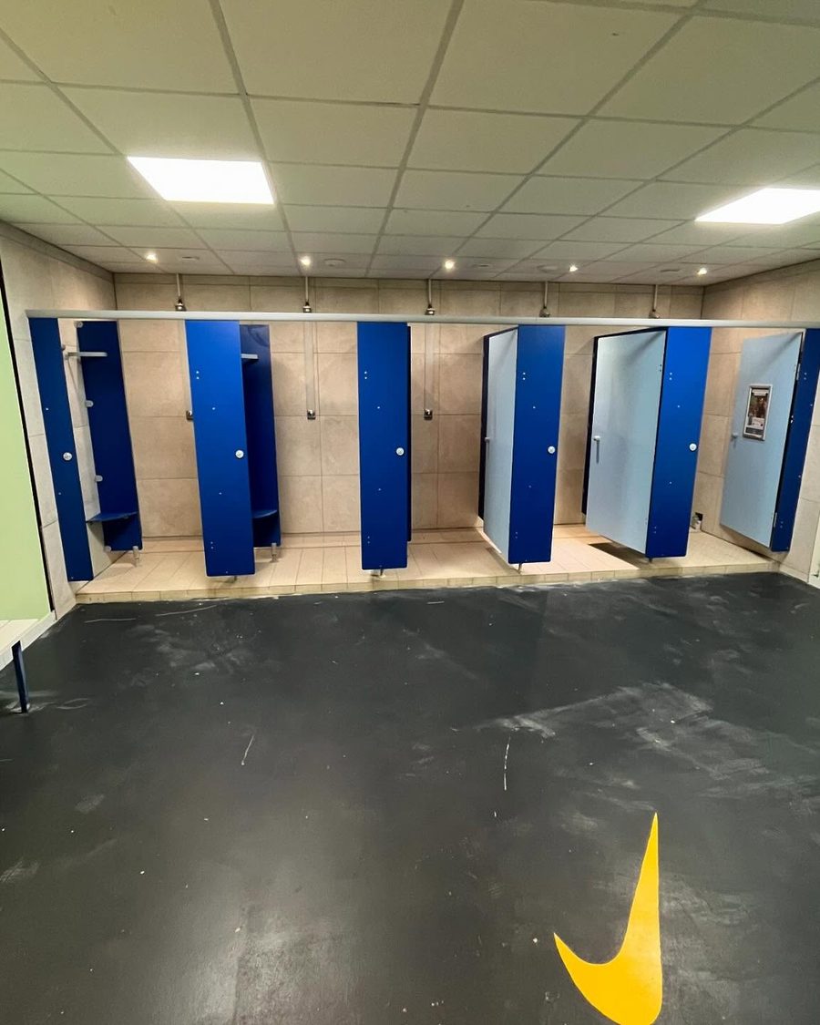Vestiaire collectif rénové : cabines de douche, plafond démontable et éclairage intégré